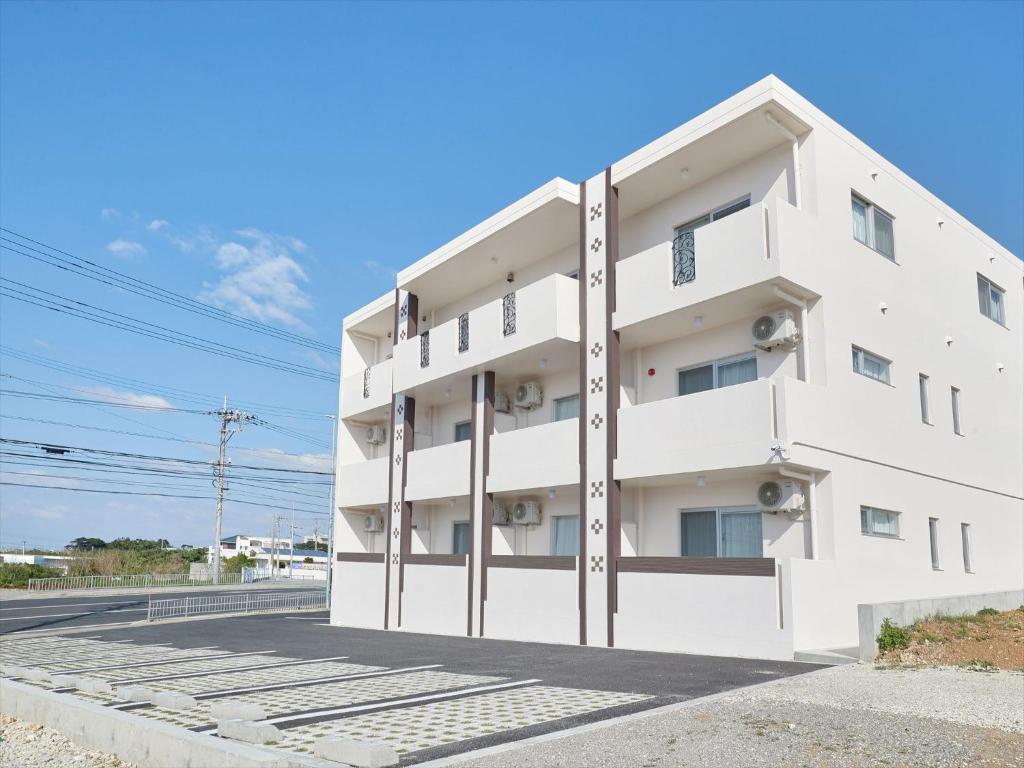 读谷村Condominium・yuyuki的道路一侧的白色建筑