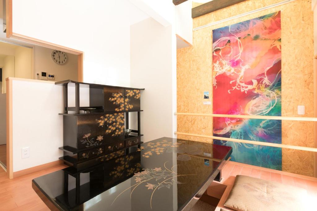 京都Guesthouse Tonton Nobu的一间设有玻璃桌和墙上绘画的房间