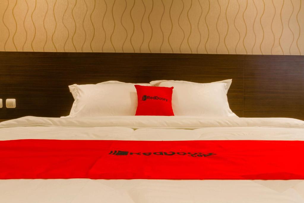 万隆RedDoorz Plus @ Dipatiukur的一张白色的床,上面有红色枕头