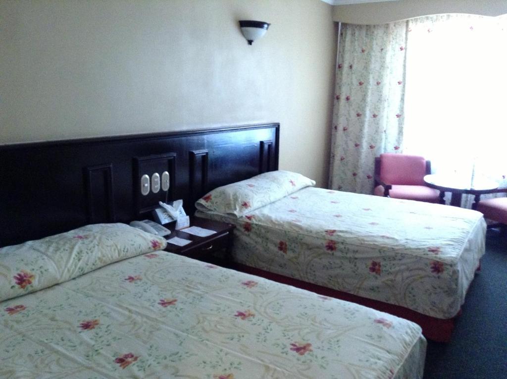 乌鲁阿潘Hotel Real de Uruapan的酒店客房设有两张床和一张桌子。