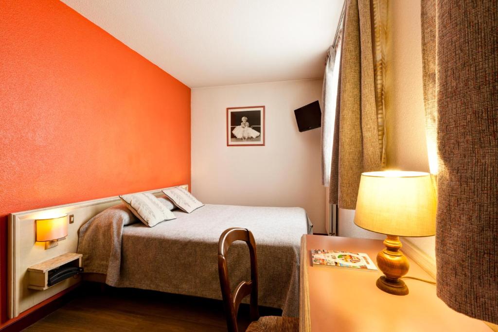 里昂卢米埃尔酒店的小房间,配有一张橙色墙壁的床