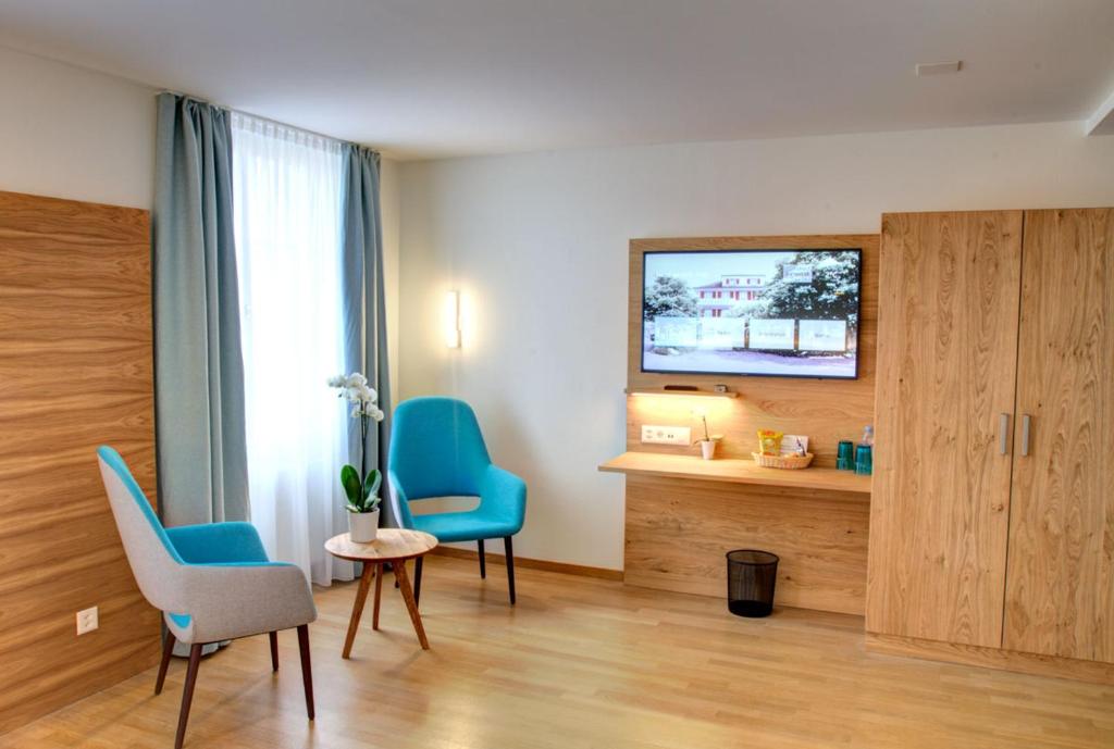 明兴施泰因Hotel & Restaurant Hofmatt的一间设有两把蓝色椅子和电视的房间