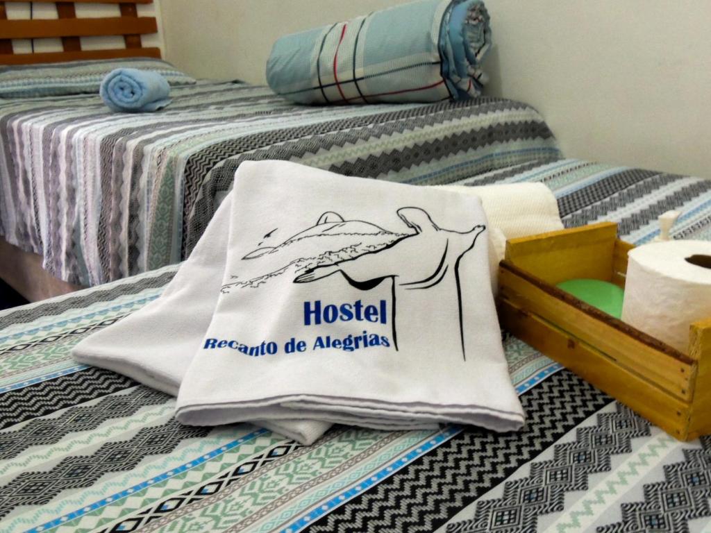 里约热内卢Hostel Recanto de Alegrias em São Cristòvão的床上的枕头,上面有旅舍标志