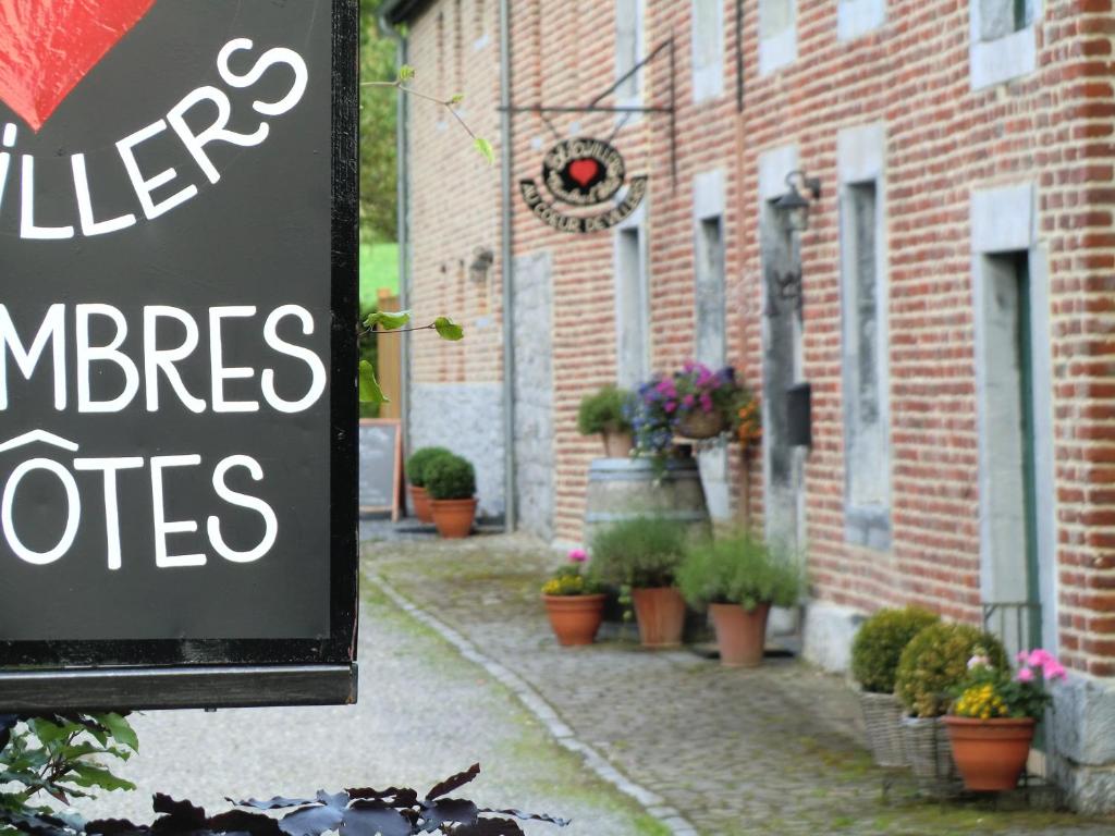 Villers-Sainte-Gertrude维莱城中心住宿加早餐旅馆的砖楼前有盆栽的标志