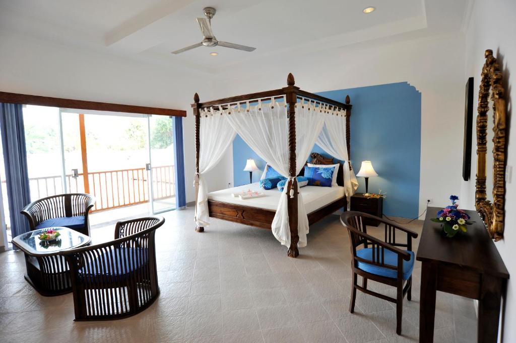 沙努尔水瓶海滩酒店的一间卧室配有天蓬床和桌椅