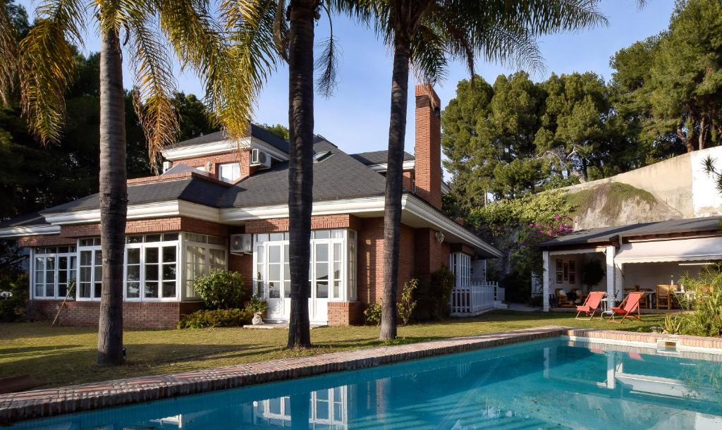 马拉加Villa Antumalal B&B的一座带游泳池和棕榈树的房子