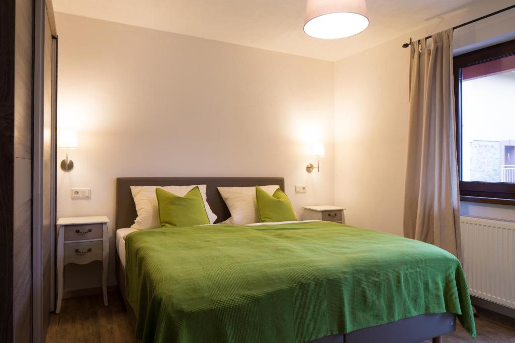 洪堡Gästehaus Bräuscheuere的一间卧室配有一张带绿色床单的床和一扇窗户。