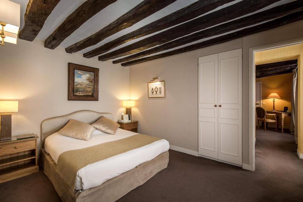 凡尔赛Logis Hôtel - La Résidence du Berry的一间卧室配有一张床,另一间卧室配有桌子