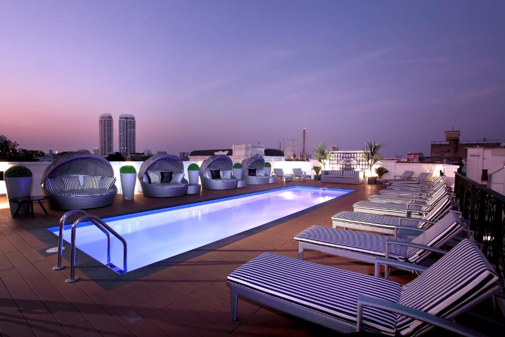 曼谷Villa De Khaosan by Chillax的一座带躺椅的建筑屋顶上的游泳池