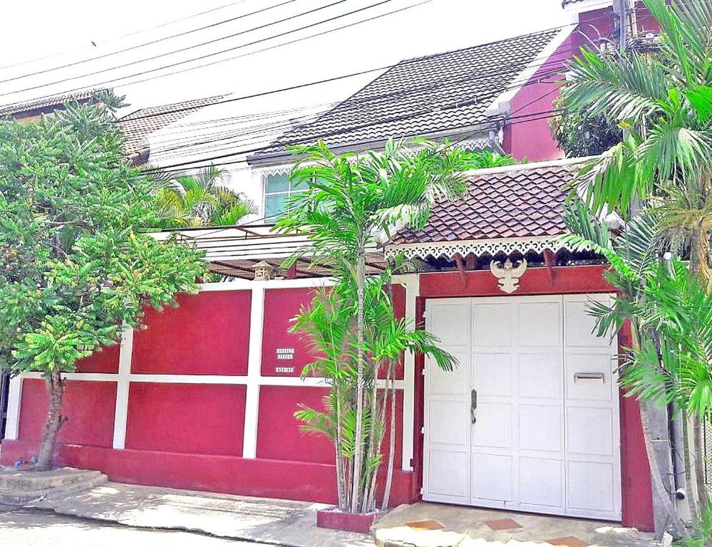 南芭堤雅三卧室泰式度假屋的前面有一个棕榈树的红色和白色车库