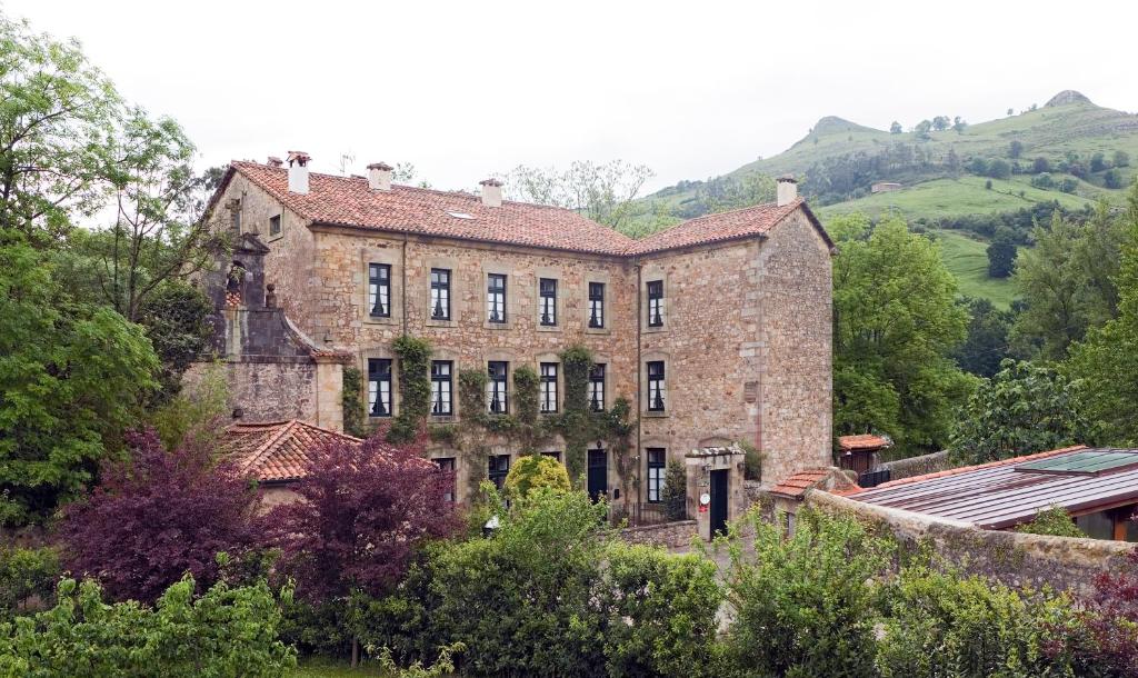 列尔加内斯阿拉尔卡索纳酒店的一座古老的砖砌建筑,后面有树木和山丘