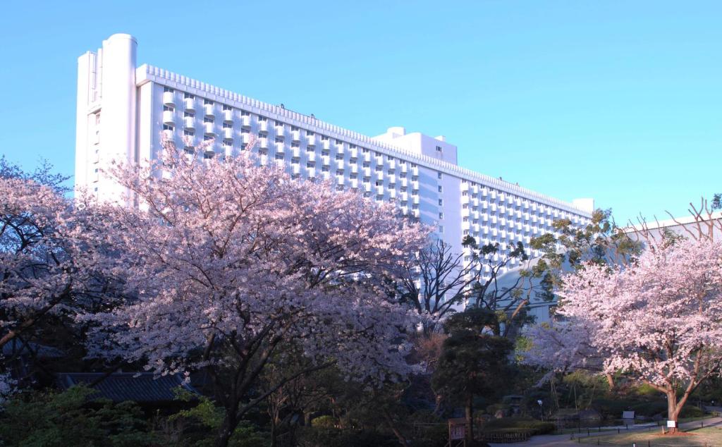 东京Grand Prince Hotel Shin Takanawa的一座大建筑前面有紫色的树木