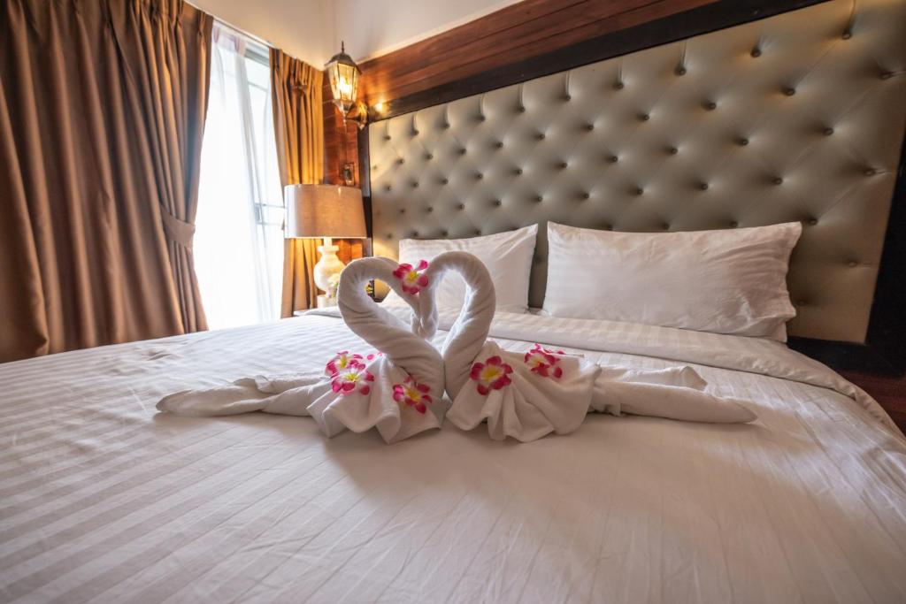 曼谷Infinite Hotel的两个穿白色的天鹅坐在床上