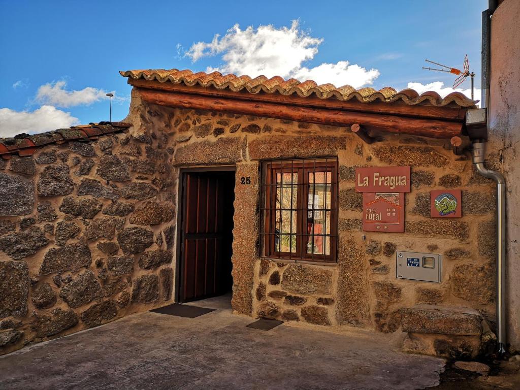 Villar de Cornejacasa rural La Fragua的石头建筑,有门和标志