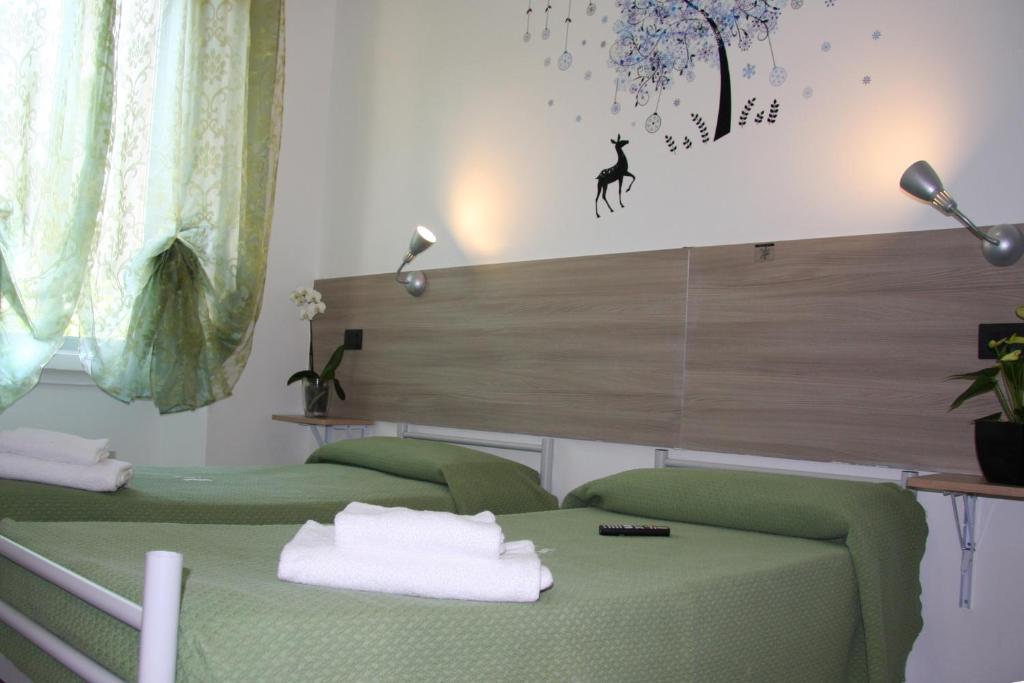 米兰阿德奇酒店的一间设有两张绿色床和一面带标志的墙壁的房间