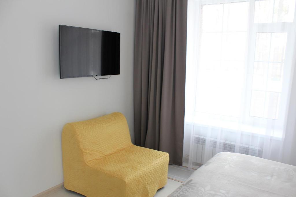 MakīnskScandi Hotel的卧室里的黄色椅子,墙上有电视