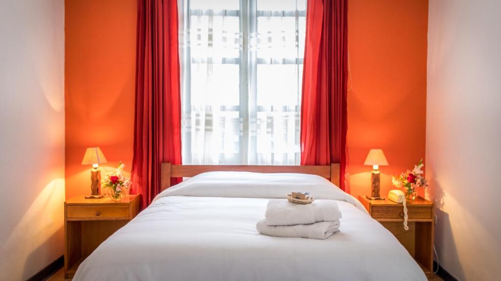 库斯科卡萨坎佩斯纳酒店的一间卧室设有橙色的墙壁和一张带毛巾的床