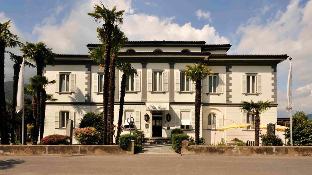 卡斯拉诺Villa Garni Gardenia的一座棕榈树掩映的白色房子