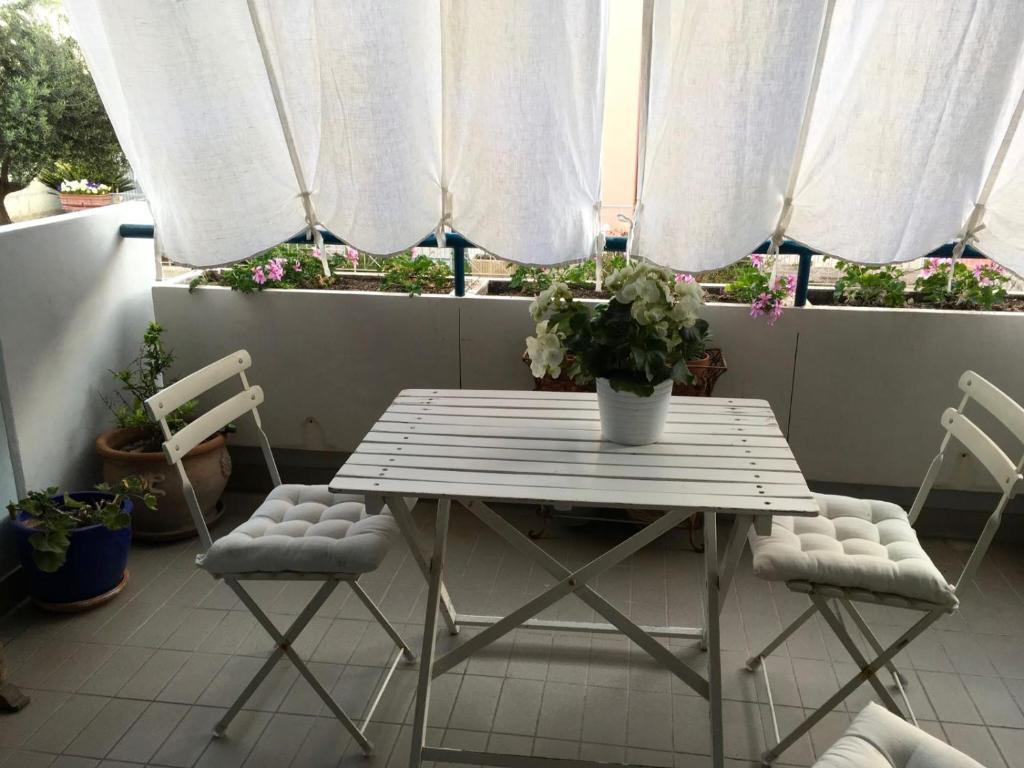 法诺LA CASA DEL MARE的阳台配有一张桌子和两把椅子,配有白色窗帘