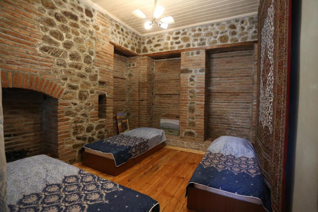 舍基伊尔哈姆穆斯塔法旅馆的一间设有两张床和砖墙的房间