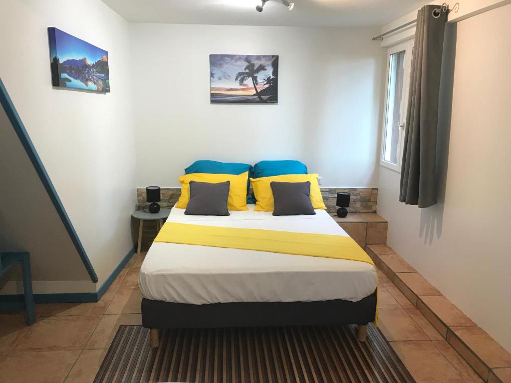 Bois dʼOliveTi Kaz Ravinala的一间卧室配有黄色和蓝色枕头的床
