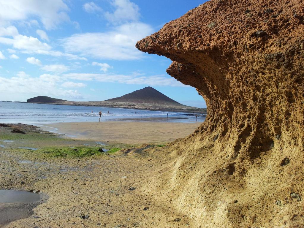 厄尔梅达诺El Medano - Cerca de la Playa的海滩上的岩石,背景是山