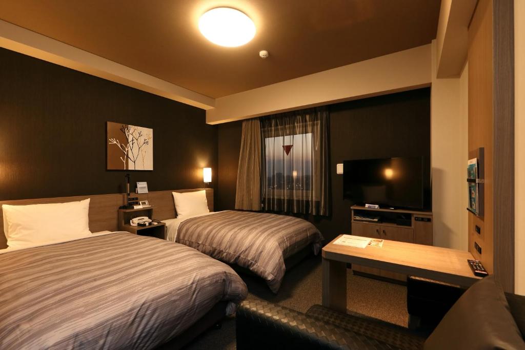新城市Hotel Route-Inn Shinshiro的酒店客房设有两张床和电视。