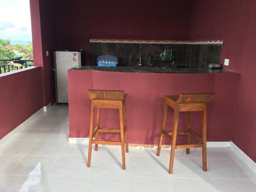 金巴兰德思德考斯特巴厘岛民宿的厨房配有2张凳子和带水槽的台面