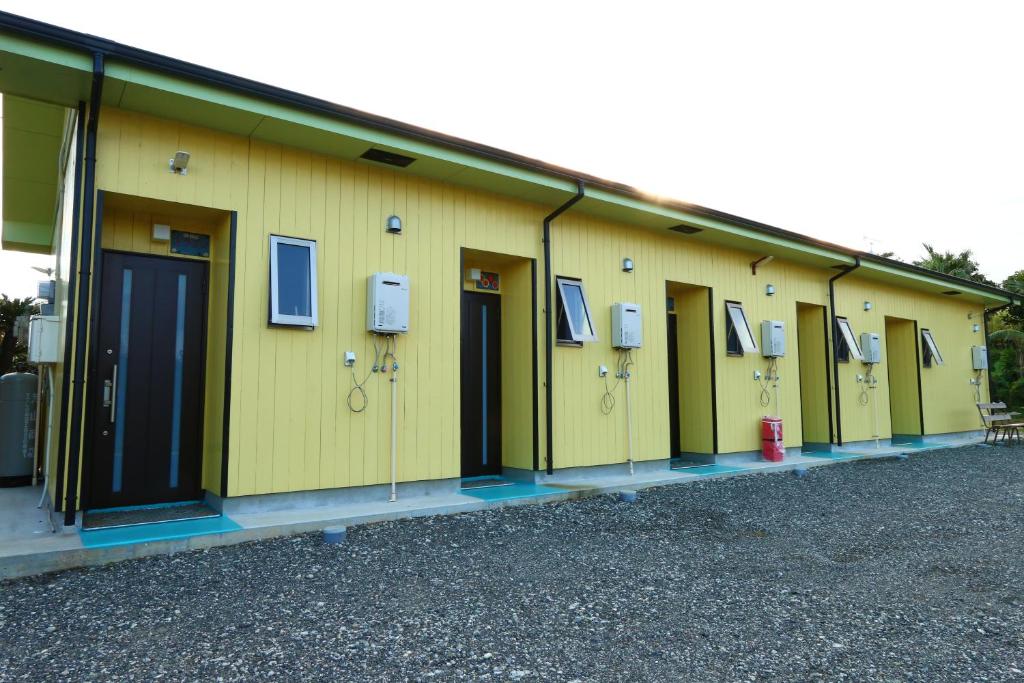 德之岛Pension Kongo Baru的一排带窗户和消防栓的黄色建筑