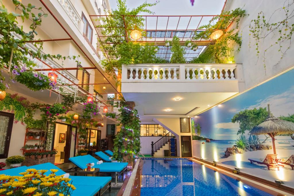 会安Pham Gia Boutique Villa的酒店游泳池设有蓝色桌子和植物