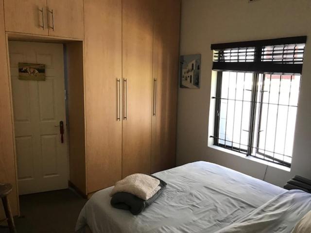 开普敦At 27 on Derby的一间卧室配有一张床、橱柜和窗户。