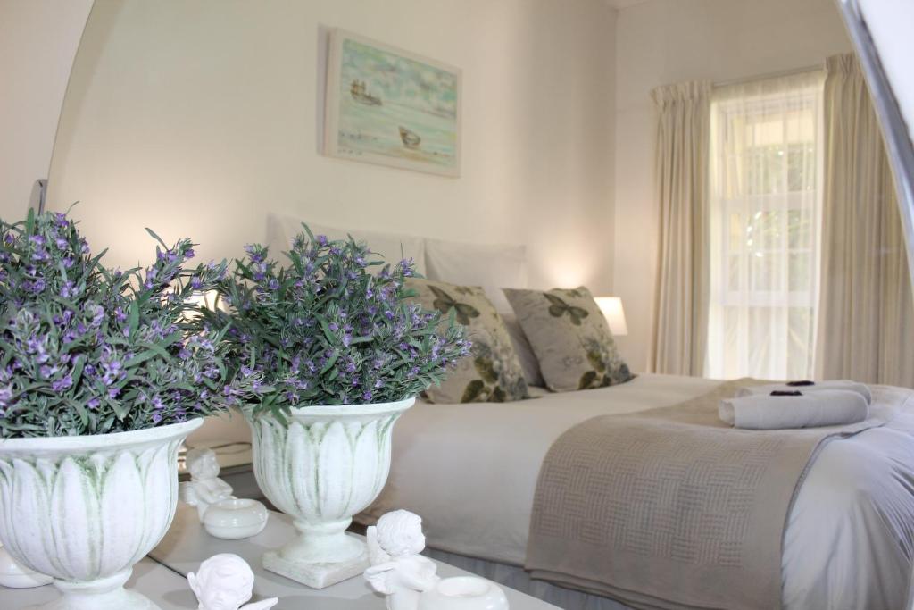 奥茨胡恩van Biljon Cottage No Loadshedding的卧室配有两只白色花瓶,床上有鲜花