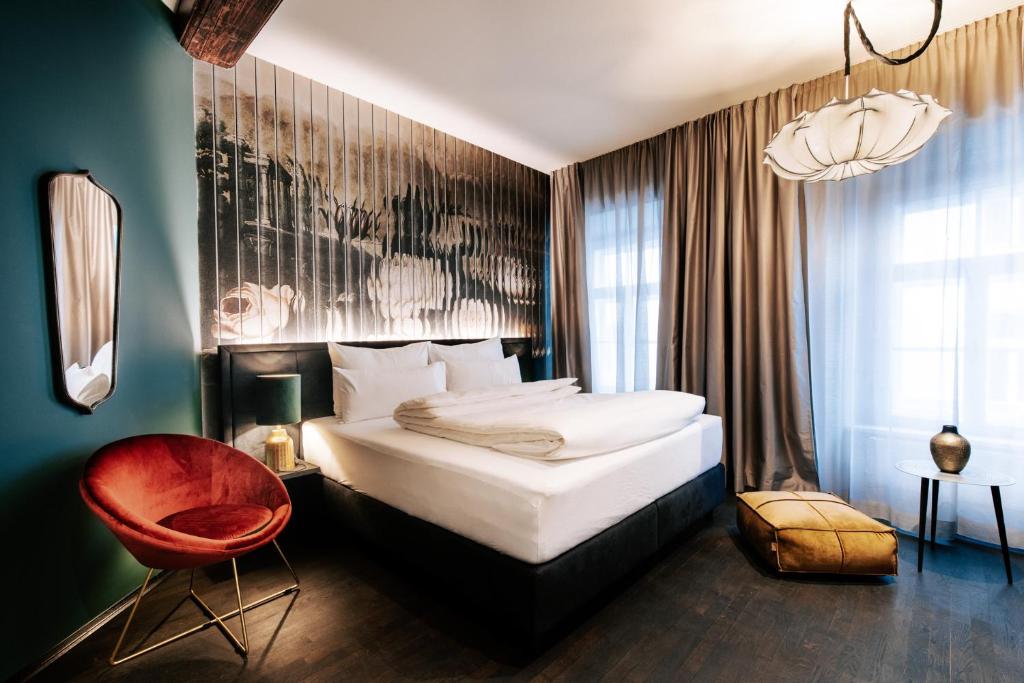 格拉茨Aiola Living Graz的一间卧室配有一张大床和一张红色椅子