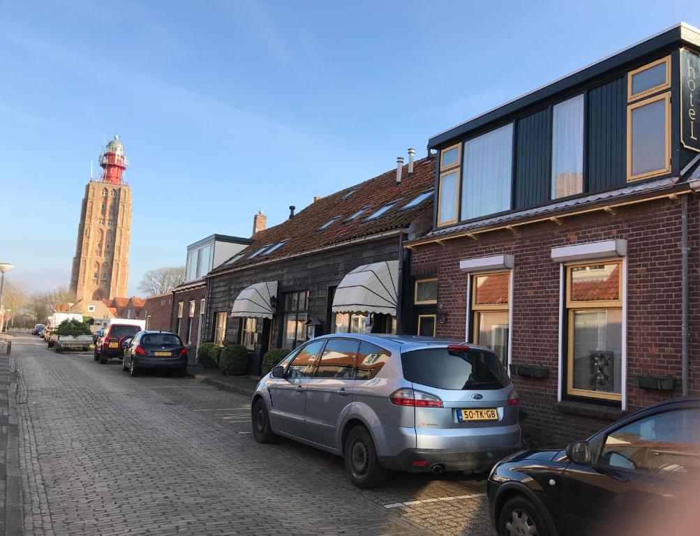韦斯特卡佩勒Hotel Pieter de Coninck的停在大楼旁的街道上的汽车
