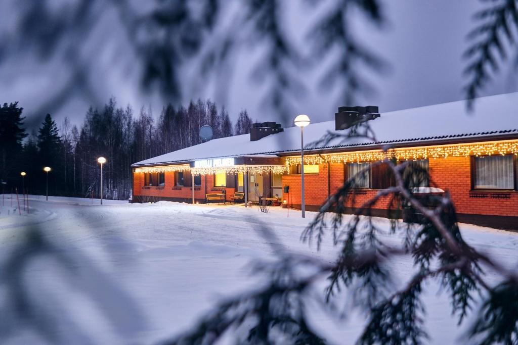 VuonislahtiHotelli Pielinen的雪中建筑物,灯光照亮