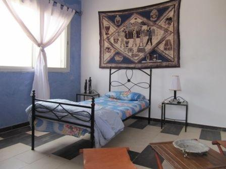 圣路易斯EDEN BEACH SAINT-LOUIS的卧室配有一张床,墙上挂有绘画作品