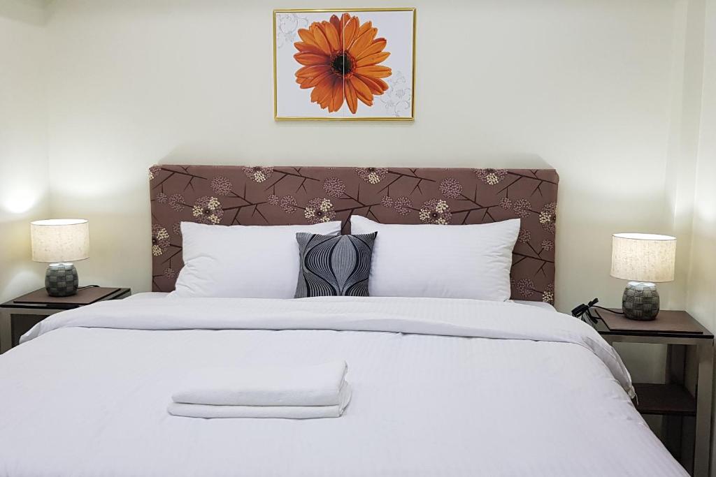 卡利博Cess Summer Boutique Hotel的一间卧室配有一张带两盏灯的大型白色床。