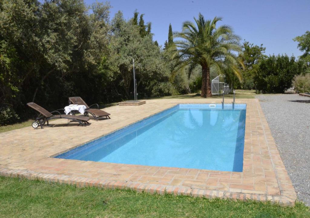 Alhendín科尔蒂霍阿尔盖比亚乡村民宿的一个带两把椅子的庭院内的游泳池