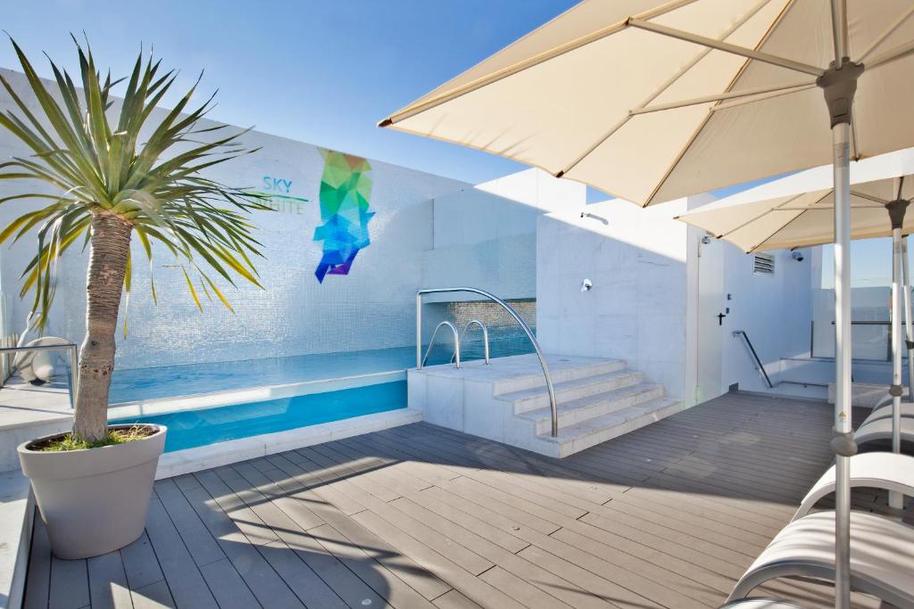 里斯本里斯本怀特酒店的一个带棕榈树和遮阳伞的游泳池