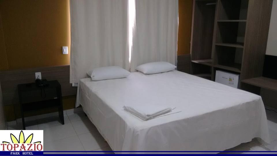 AfrânioTopázio Park Hotel的一间卧室配有一张带白色床单的床和一扇窗户。