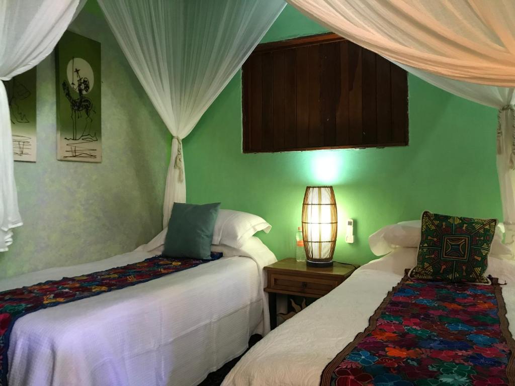 萨尤利塔Casa Juanita的配有两张床铺的绿色墙壁和窗帘