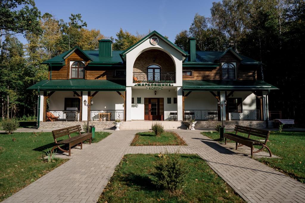 ZharkovshinaBelovezhskaya Pushcha Hotel complex Zharkovshina的前面有两长椅的房子