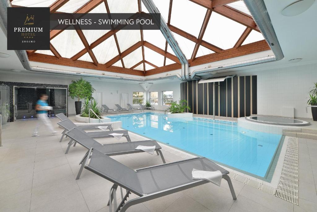 兹诺伊莫PREMIUM Wellness & Wine Hotel Znojmo的大楼内带椅子的大型游泳池