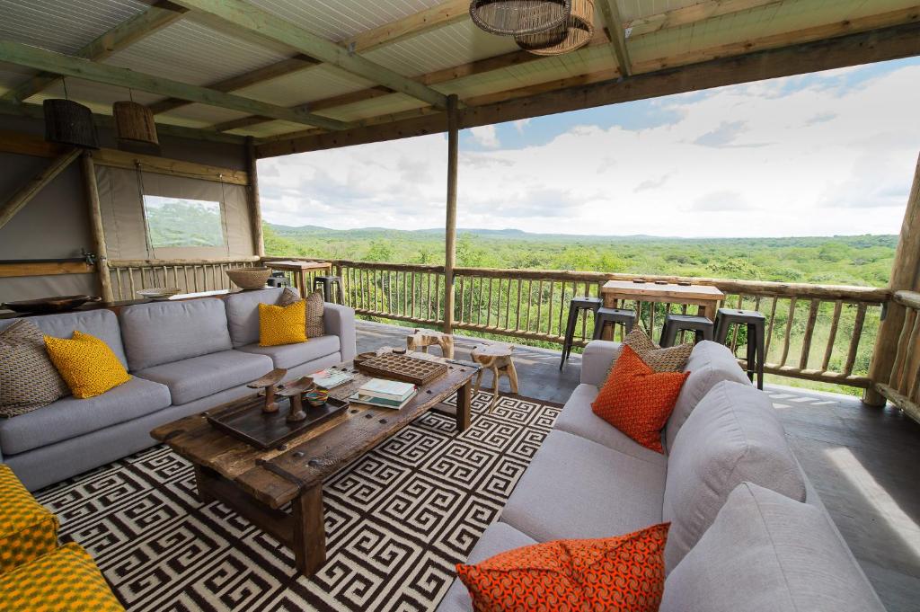 赫卢赫卢韦Zululand Lodge的客厅配有沙发,阳台上配有桌子
