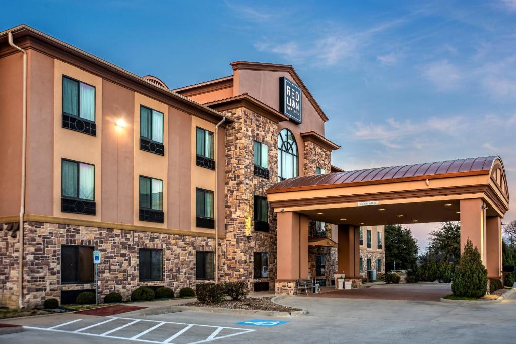 矿泉井城Red Lion Inn & Suites Mineral Wells的前面有一个停车位的酒店