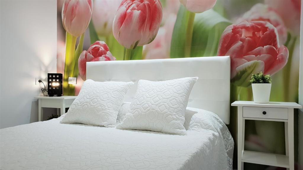 阿罗纳Home Sweet Home的卧室配有带粉红色郁金香的白色床