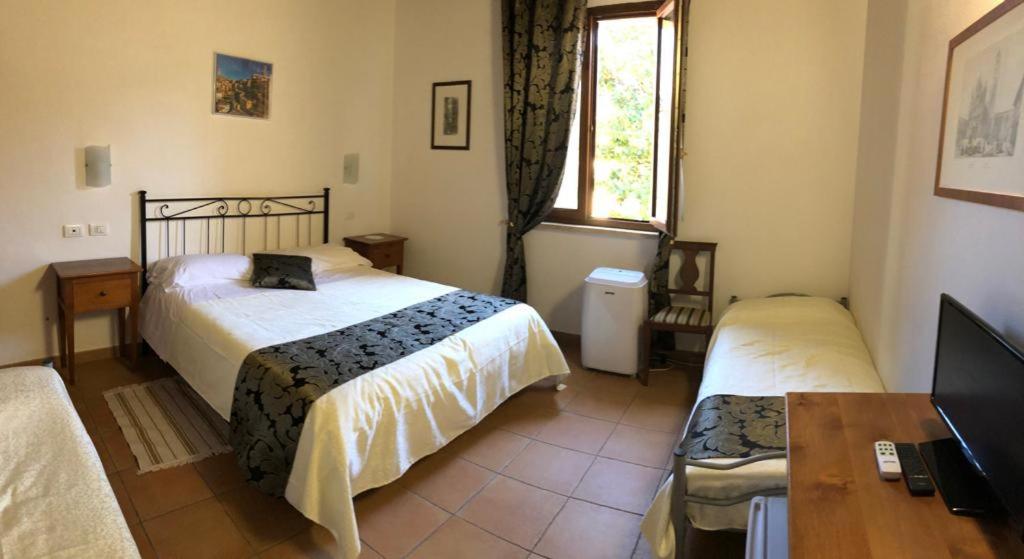 锡耶纳锡耶纳托斯卡纳旅馆的一间卧室配有两张床、一张桌子和一台电视。
