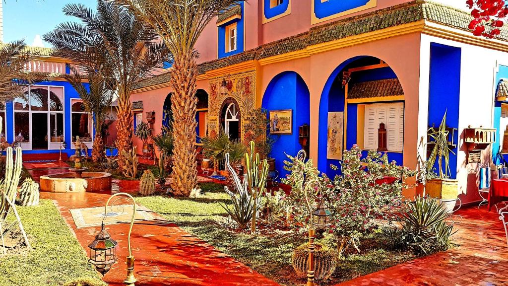 扎古拉Riad Jasmine Sud的拥有蓝色和橙色墙壁和棕榈树的房子