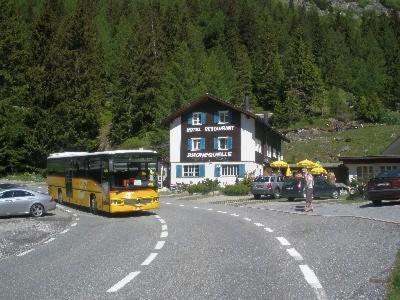 上瓦尔德法尼奎勒酒店的一辆黄色的公共汽车沿着房子旁边的一条路上行驶