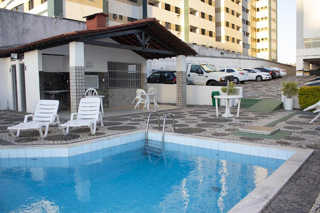 萨尔瓦多Apto Inteiro Stiep的一座带桌椅的游泳池以及一座建筑